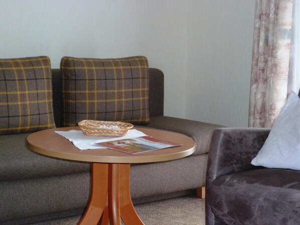 A living room with a sofa, a round table, and a basket. - Pension Haus Waldfrieden (Willingen)
