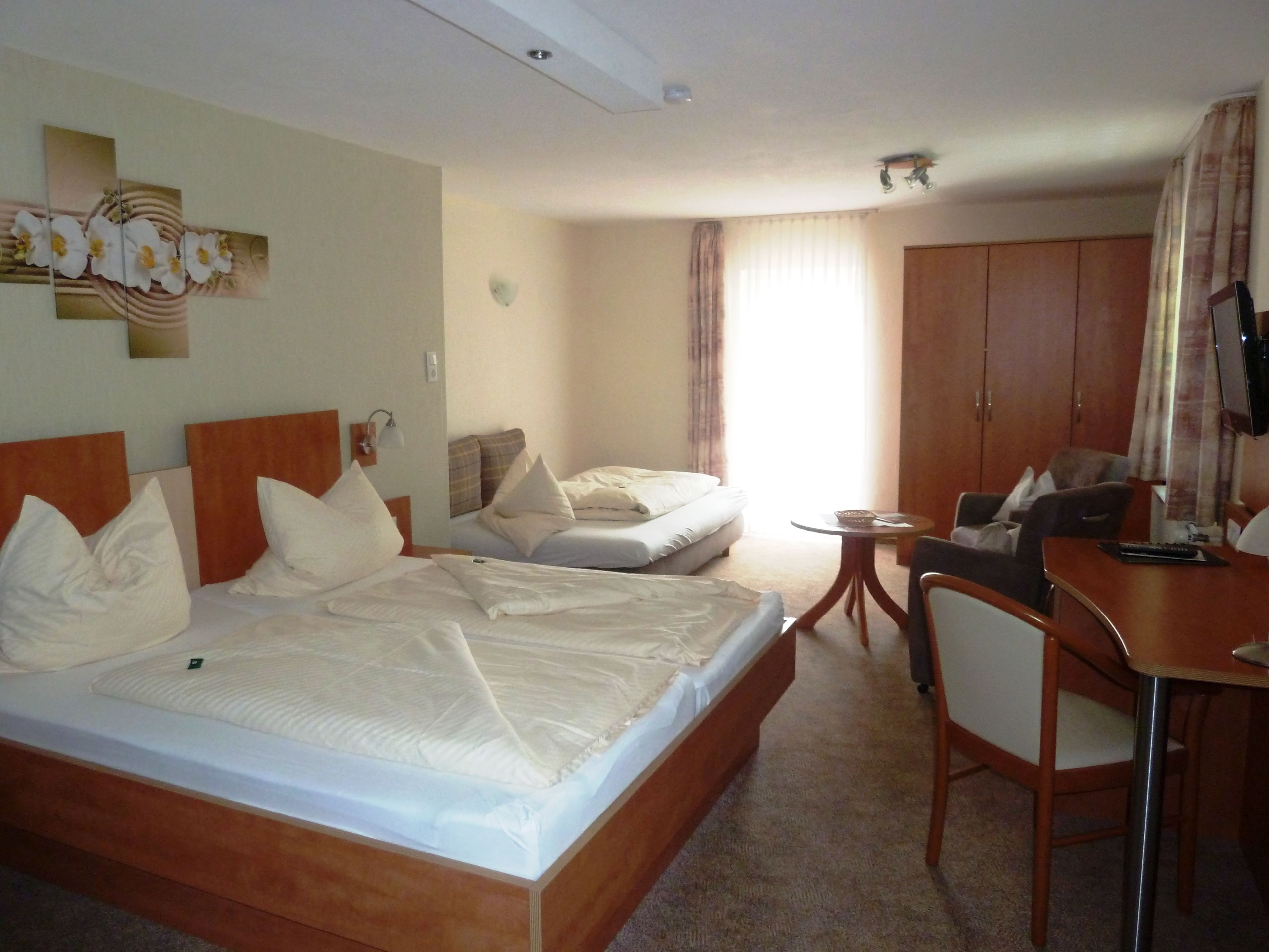 Ein Hotelzimmer mit zwei Betten, einem Schreibtisch, einem Stuhl, einem Fernseher und einem großen Kleiderschrank.