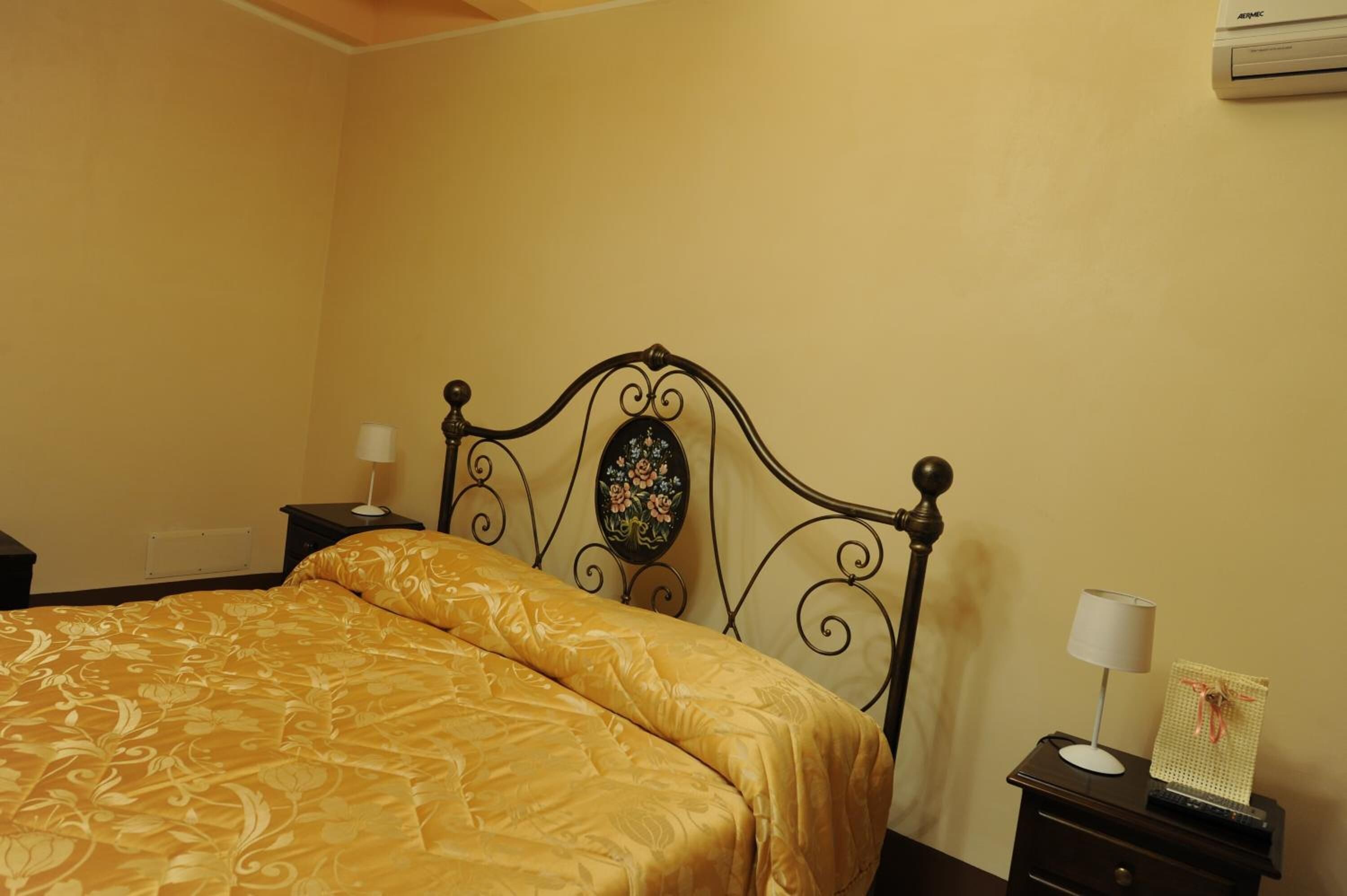 Une chambre à coucher comprenant un lit, une table de chevet, une lampe et un climatiseur fixé au mur.