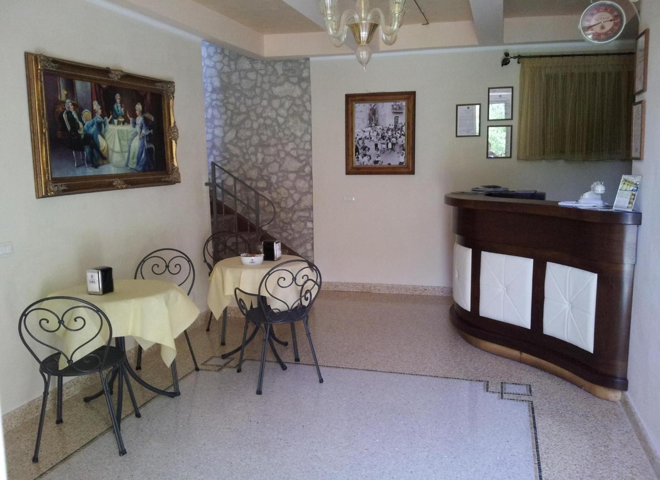 Zona pranzo con tavolo e sedie, una scala, un quadro incorniciato e una reception.