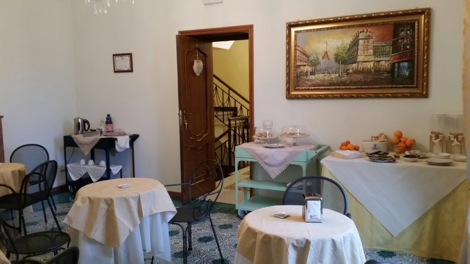 Un espace repas avec des tables rondes, un escalier et un tableau accroché au mur.