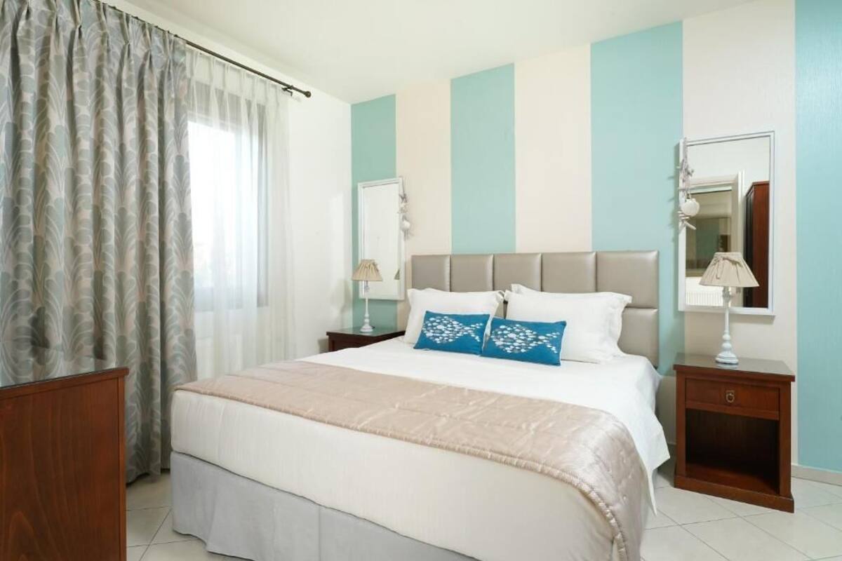 Quarto de hotel com uma cama, duas mesas de cabeceira, um espelho e cortinas.