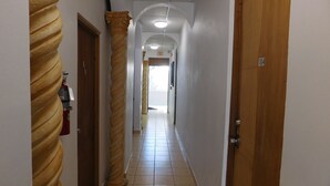 A hallway with a spiral column, a fire extinguisher, and a door labeled "104". - Henry's GuestHouse - Hostel (San Juan)