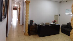 A reception area with a desk, a chair, a plant, and a framed picture on the wall. - Henry's GuestHouse - Hostel (San Juan)