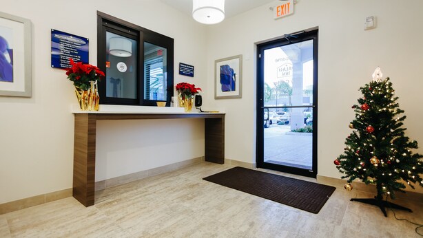 A reception area with a reception desk, framed artwork, a Christmas tree, and a door leading outside. - Palace Inn City Center (Houston)