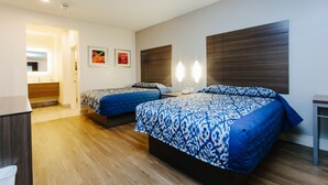A hotel room with two beds, a wooden floor, a desk, and a bathroom visible through an open door. - Palace Inn City Center (Houston)