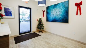 A reception area with a Christmas tree, a large abstract painting, and a door leading outside. - Palace Inn City Center (Houston)