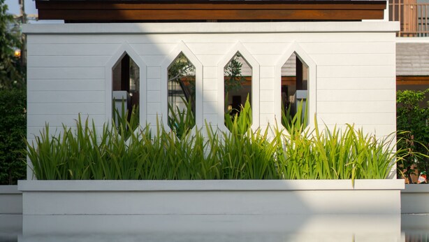 A modern building with a flat roof, white exterior walls, and a reflective pool in front. - Villa Sanpakoi (Chiang Mai)