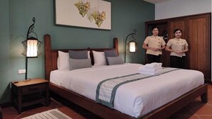 A hotel room with a large bed, two bedside tables, a nightstand, and a wooden wardrobe. - Villa Sanpakoi (Chiang Mai)