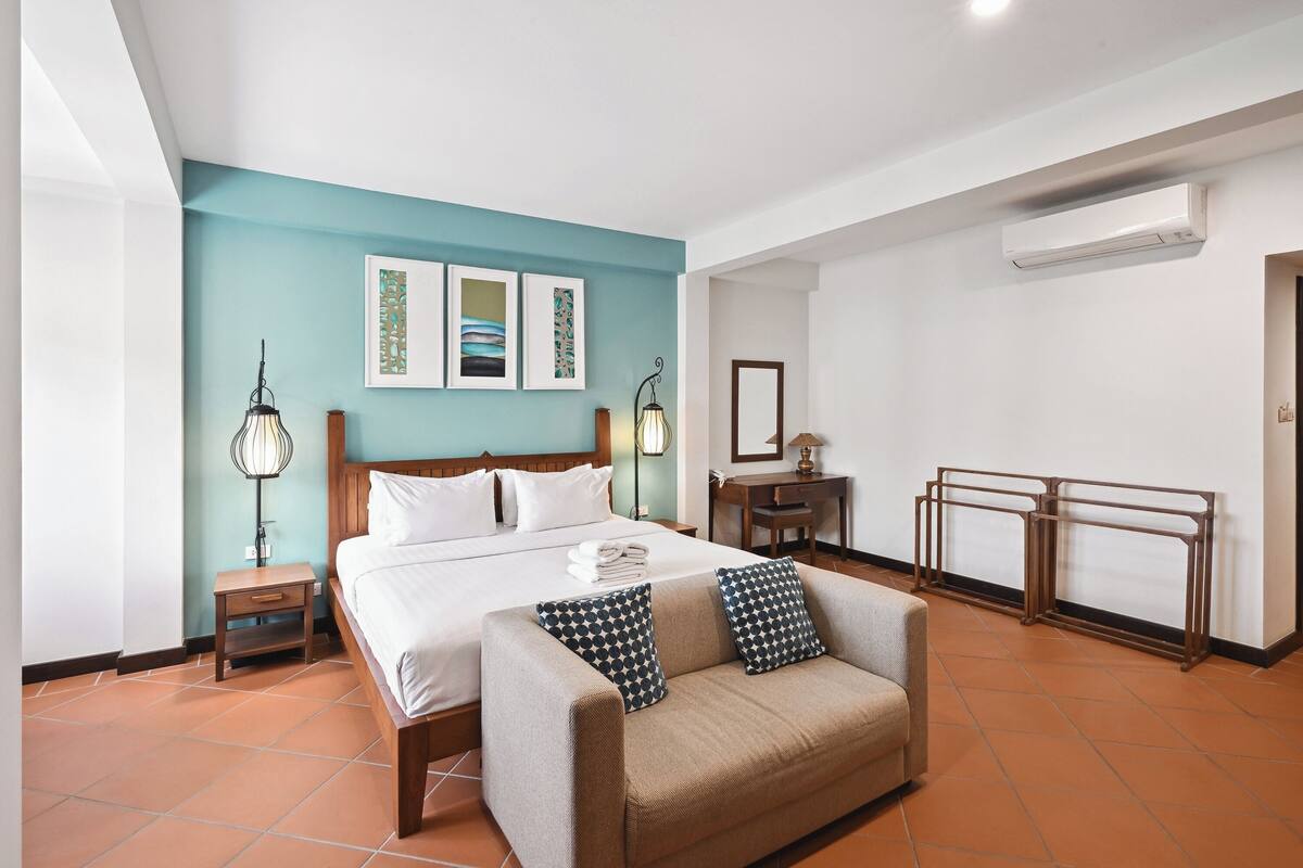 A hotel room with a bed, a sofa, a desk, and a chair.