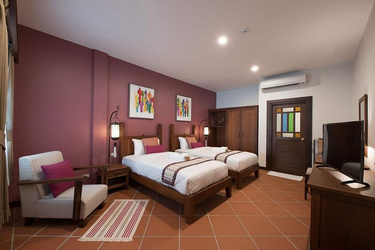 A hotel room with two beds, a desk, a chair, and artwork on the walls.