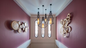 A staircase with a wooden handrail, a wall with circular wall decor, and a ceiling with hanging pendant lights. - Villa Sanpakoi (Chiang Mai)
