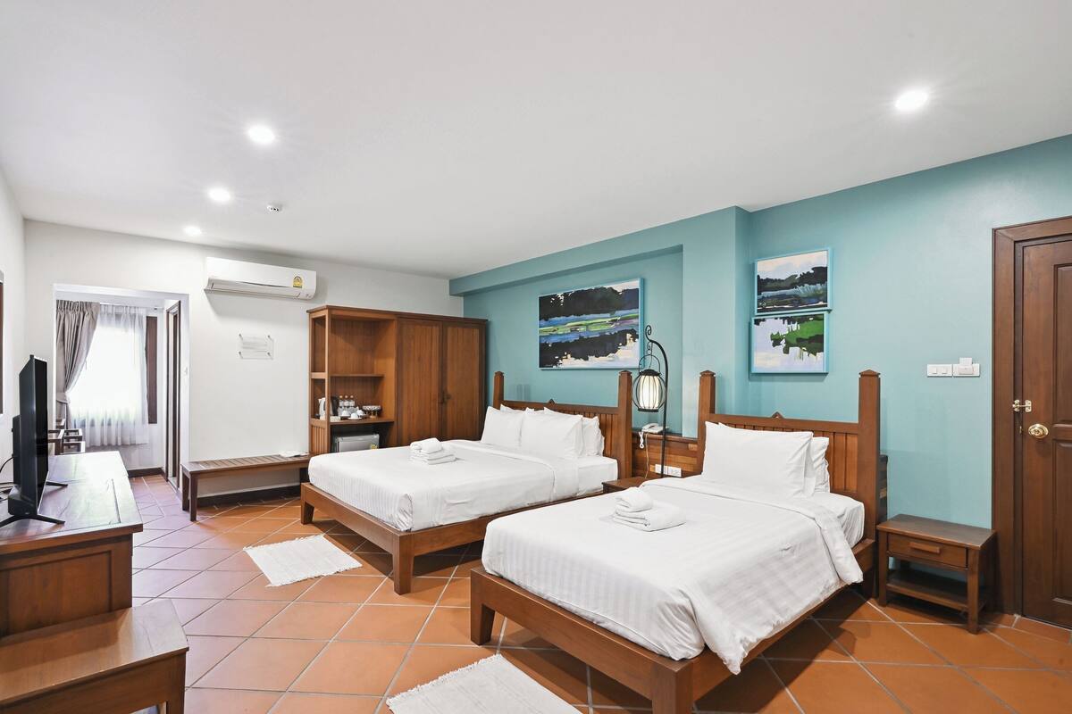 A hotel room with two beds, a desk, a TV, and a wardrobe.
