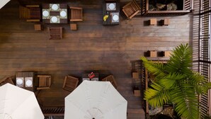 An outdoor seating area with wooden tables and chairs, umbrellas, and potted plants. - Villa Sanpakoi (Chiang Mai)