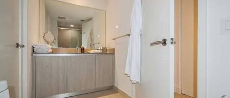 Un baño moderno con tocador de madera, un espejo grande y una toalla blanca colgada en la pared.