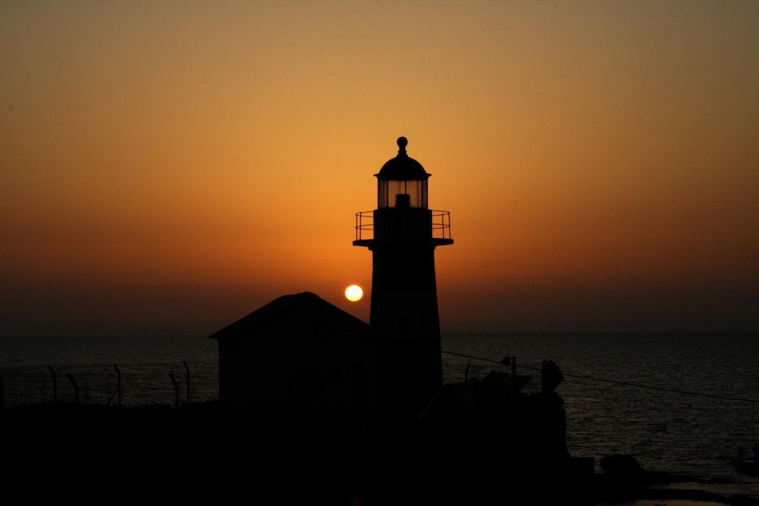 A lighthouse silhouette against a sunset.