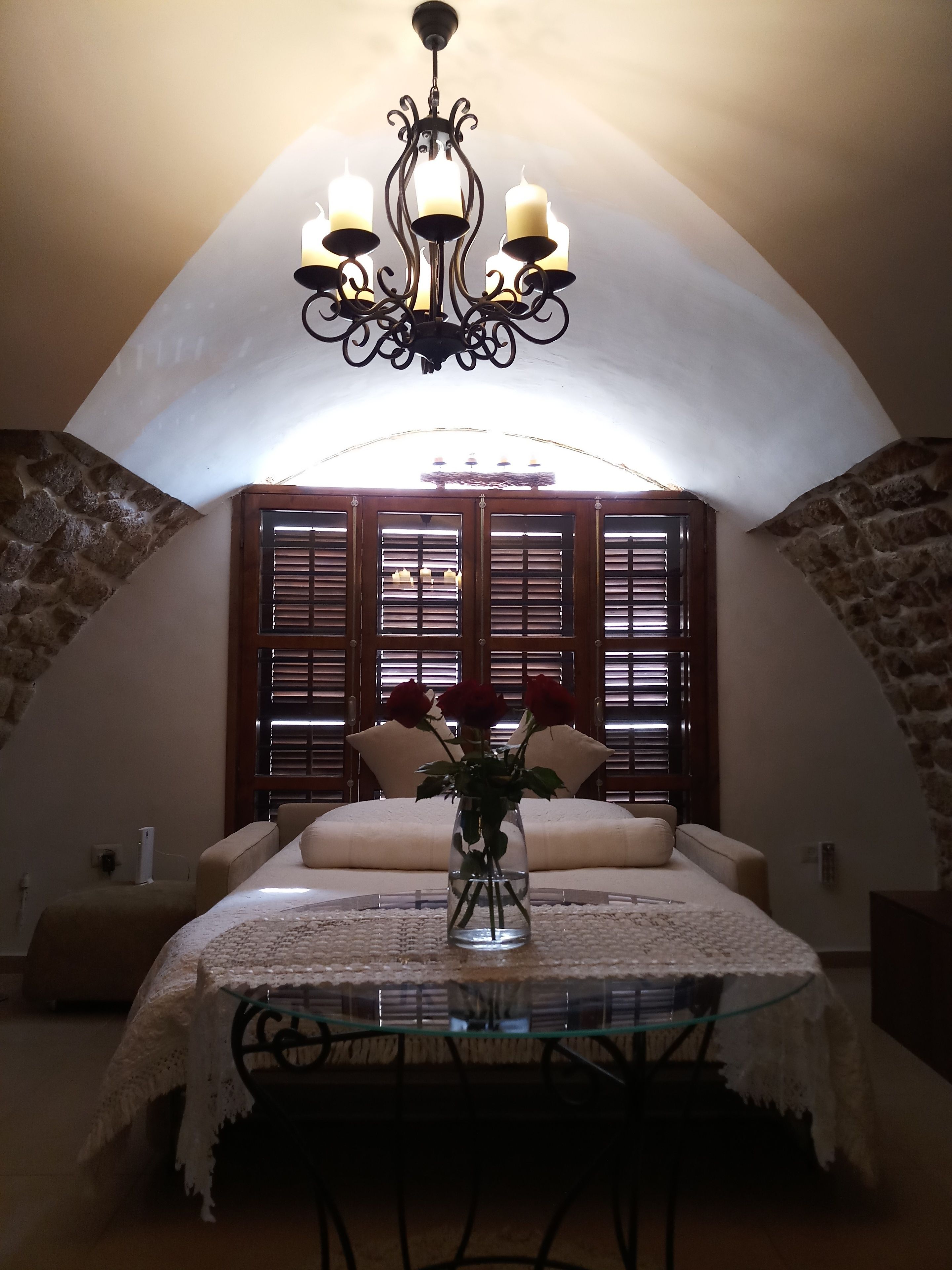 A cozy room with a chandelier, a table with a lace tablecloth, and a vase with flowers.
