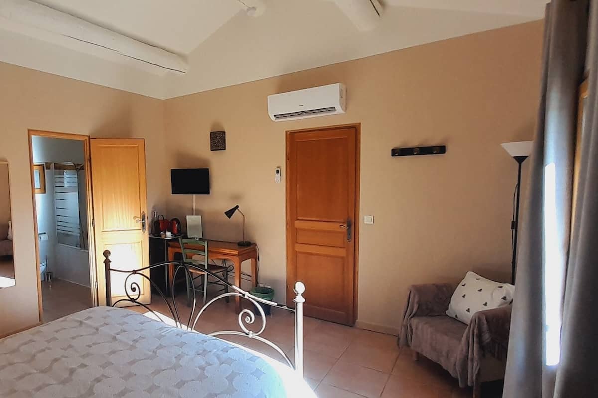 Une chambre à coucher comprenant un lit, un bureau, une chaise, une armoire et un appareil de climatisation.