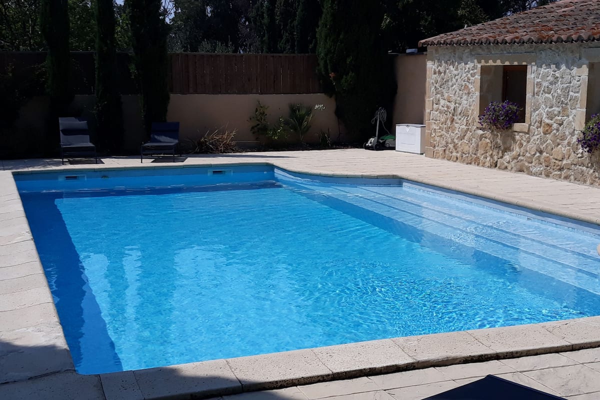 Une piscine rectangulaire à l’eau d’un bleu limpide, entourée d’une terrasse carrelée.