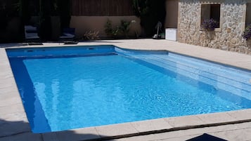 A rectangular swimming pool with clear blue water, surrounded by a tiled deck.
