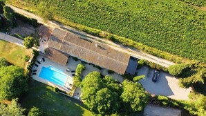 Vue aérienne d’une propriété dotée d’une piscine, d’un patio couvert et d’une allée menant à une voiture garée.