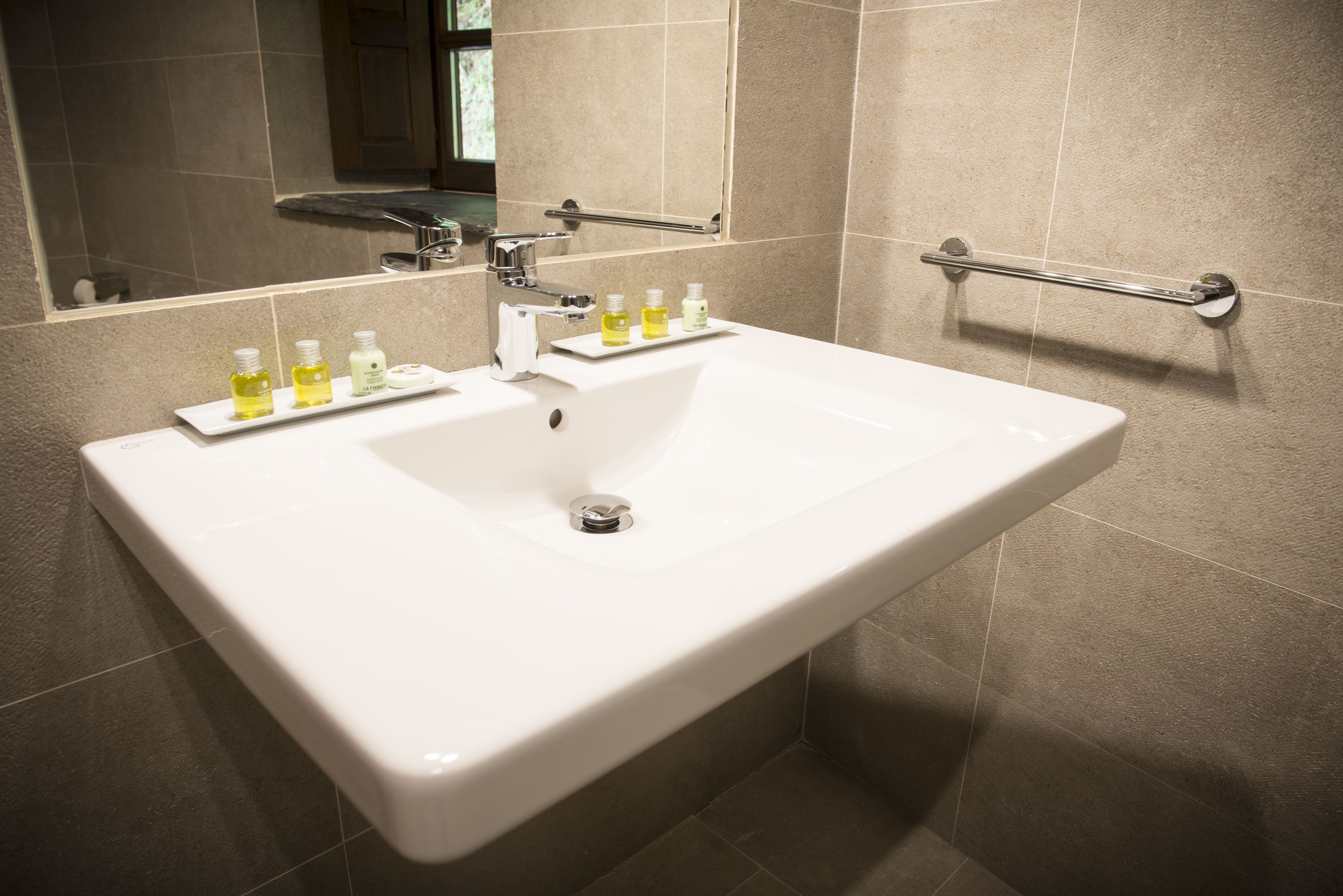 A bathroom with a white sink, mirror, and two towel bars.
