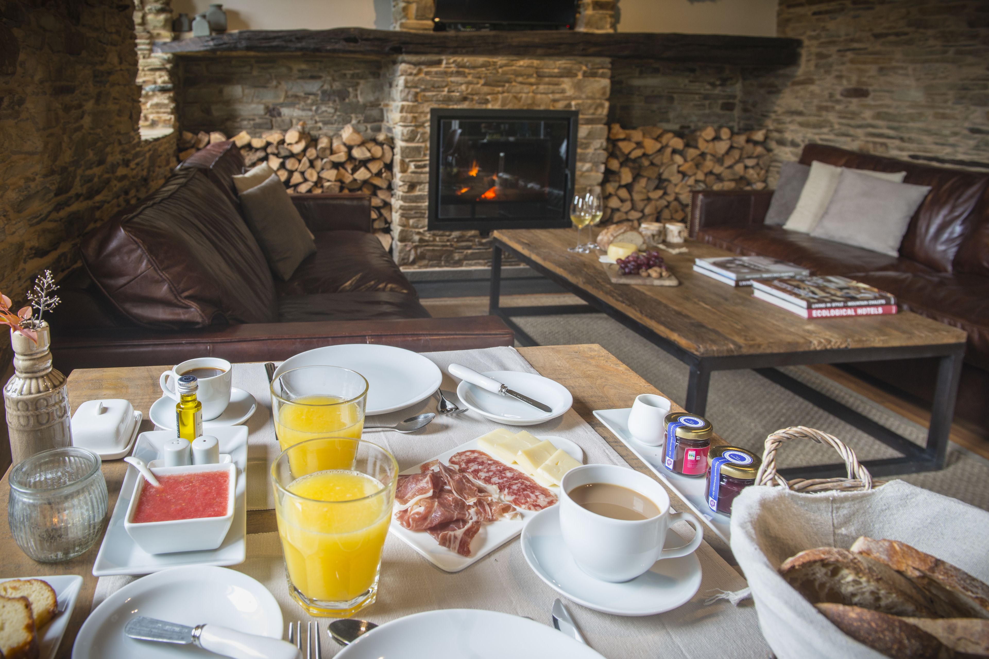 A cozy living room with a fireplace, a dining table set with breakfast items, and comfortable seating.