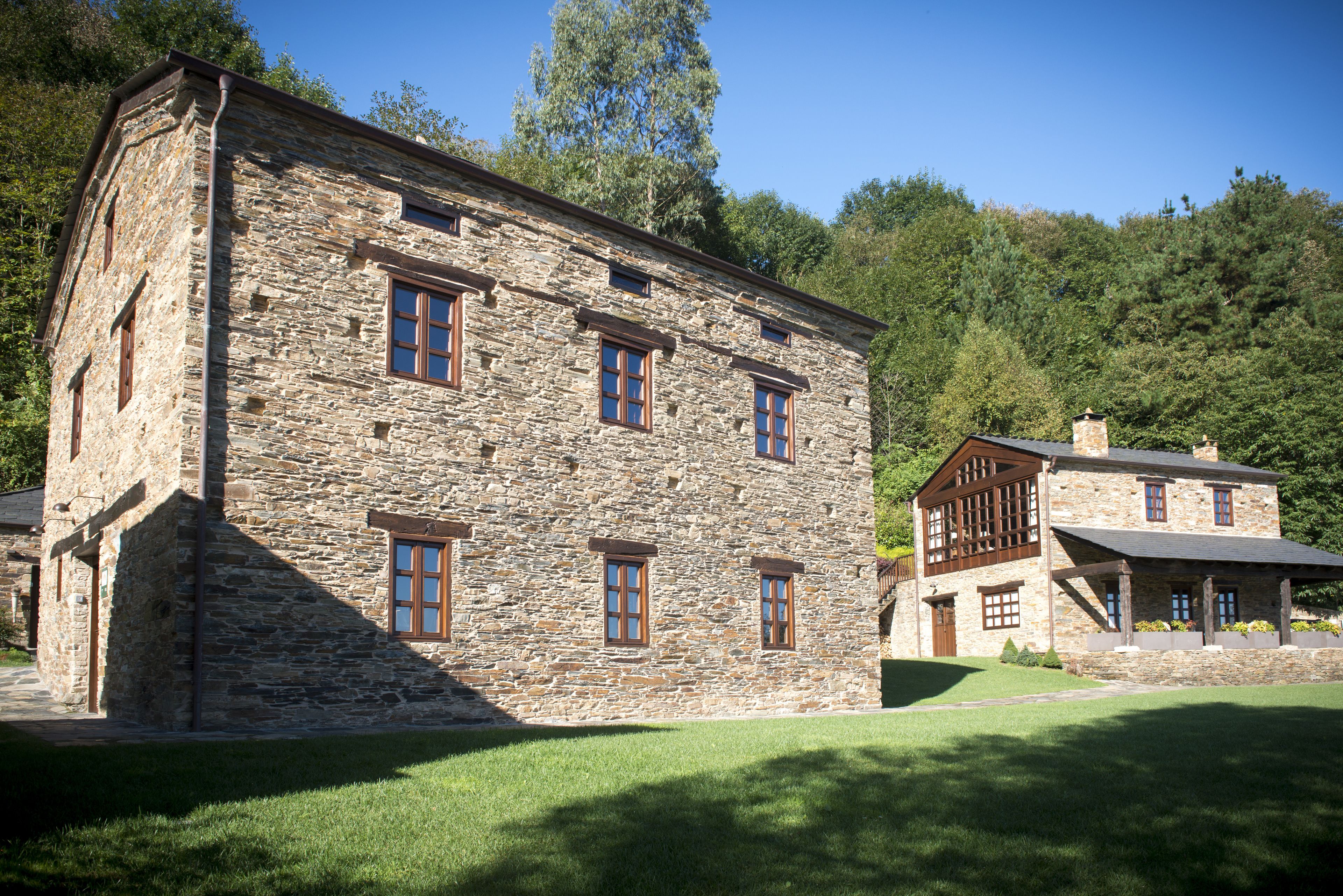 A stone building with multiple windows and a well-maintained lawn.
