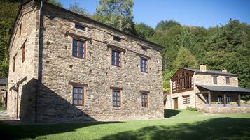 A stone building with multiple windows and a well-maintained lawn.