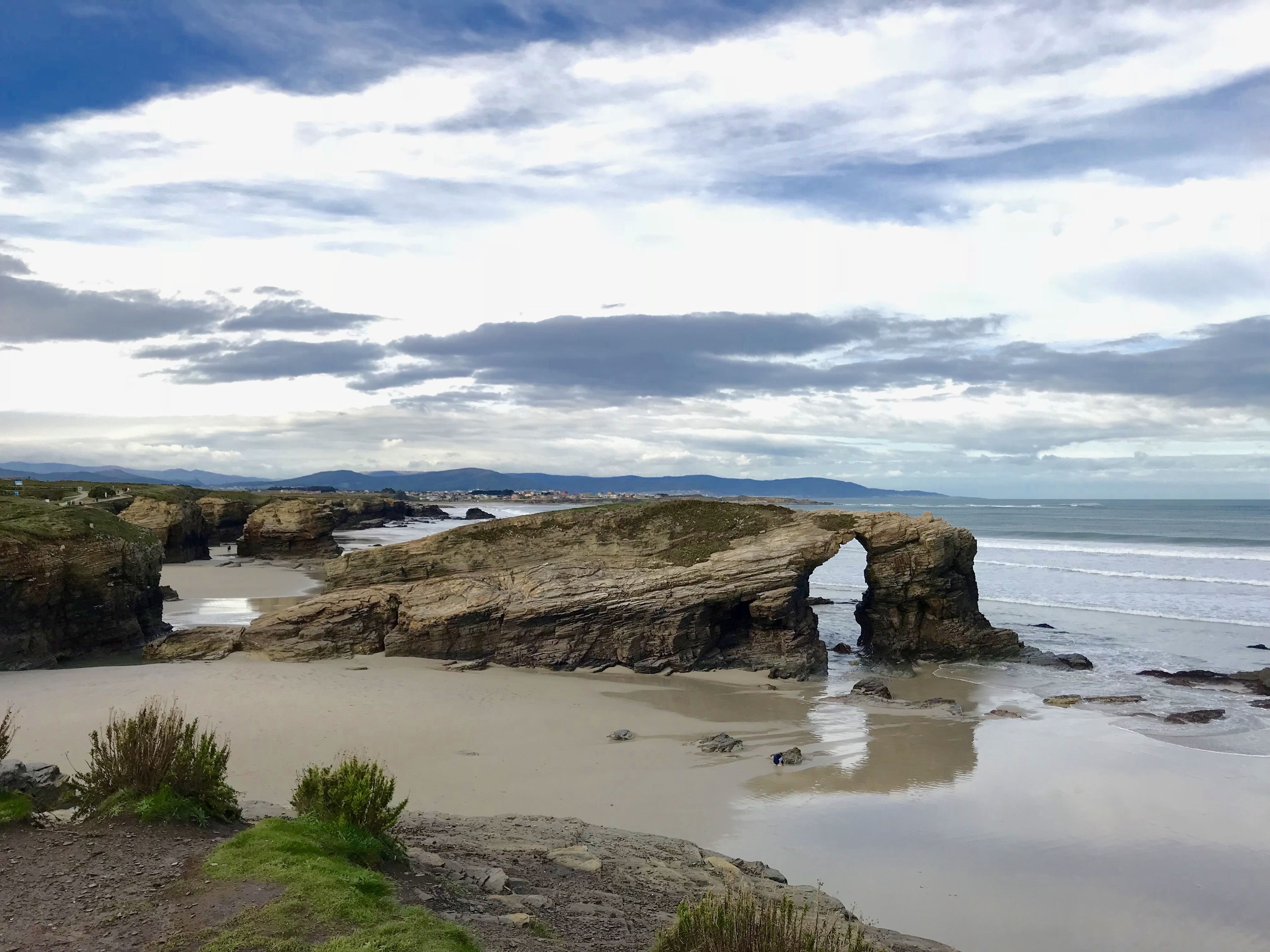 A coastal landscape with a prominent rock formation featuring a natural arch.