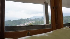 A room with a large window offering a view of a town and mountains. - The View Villa (Cisarua)