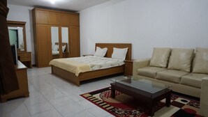 A bedroom with a bed, a sofa, a wardrobe, and a coffee table. - The View Villa (Cisarua)