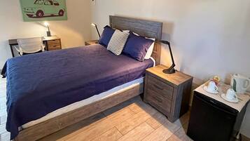 A neatly arranged bedroom with a bed, bedside tables, a chair, and a coffee station.