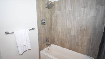 Une salle de bain équipée d’une baignoire, d’un porte-serviettes et d’un pommeau de douche.
