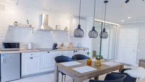 A modern kitchen with white cabinetry, a wooden dining table, and black chairs. - Royal Suite near Lake (Sumy)