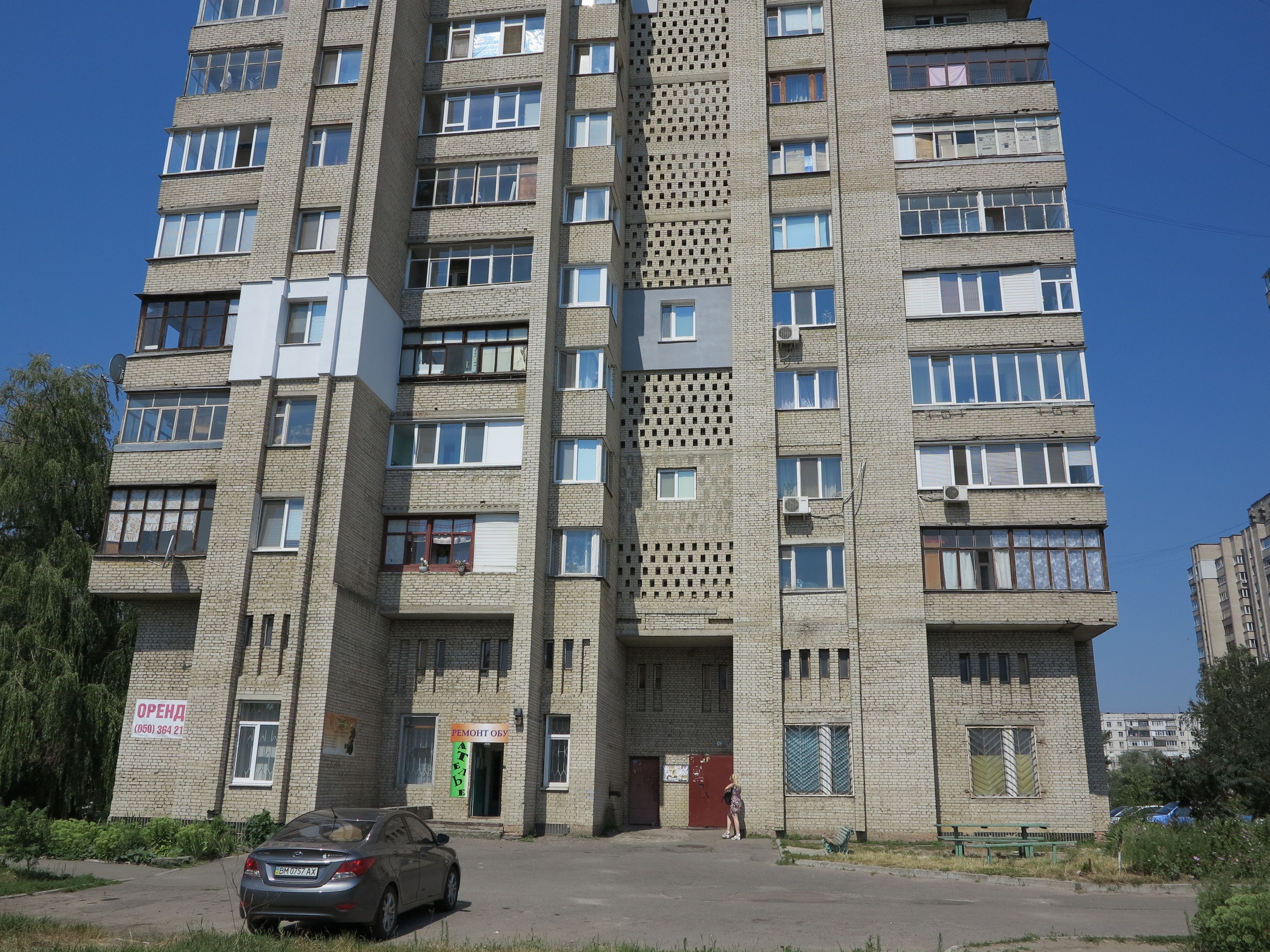 A multi-story residential building with a central entrance, multiple windows, and a visible door.