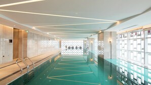 A modern indoor swimming pool with a clear water path, glass walls, and a ceiling with linear lighting. - Hilton Garden Inn Zhuhai Hengqin (Zhuhai)