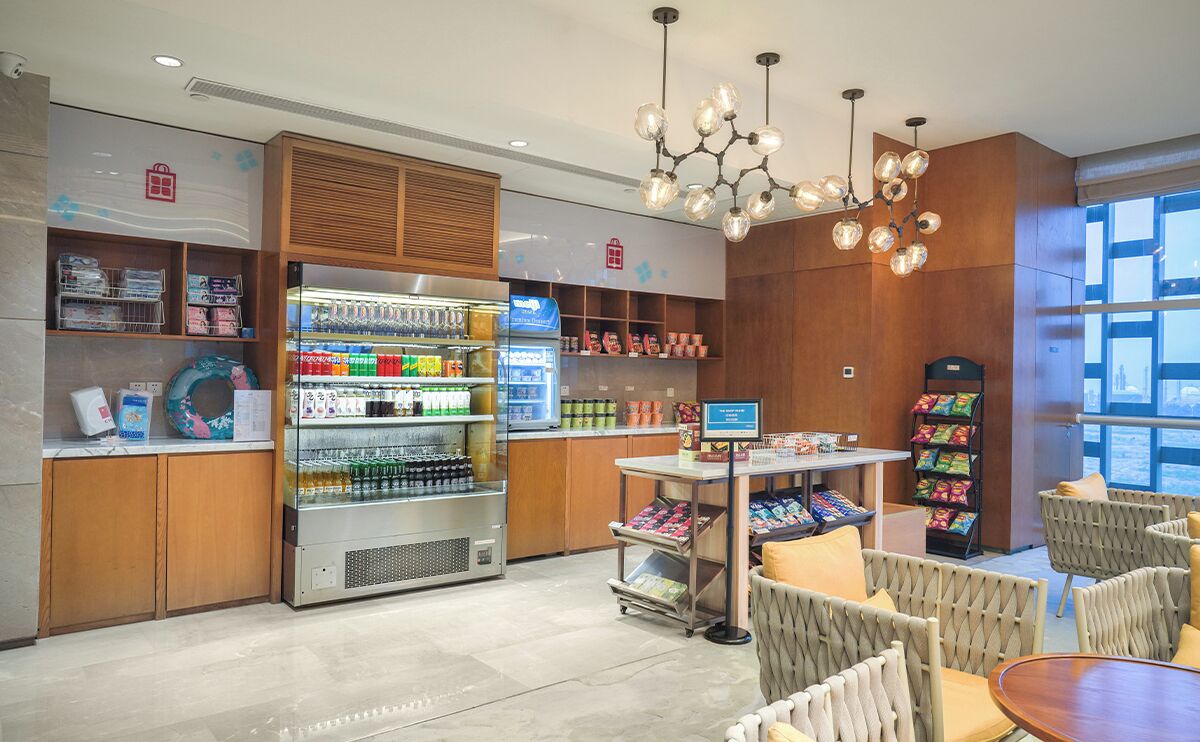 A modern hotel lobby with vending machines, seating areas, and a large window offering a view.