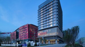 A modern hotel with a prominent red and blue facade, multiple floors, and a large entrance area with a sign. - Hilton Garden Inn Zhuhai Hengqin (Zhuhai)