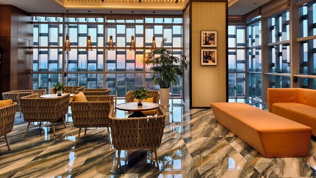 A modern interior with a high ceiling, large windows, and a mix of seating areas. - Hilton Garden Inn Zhuhai Hengqin (Zhuhai)