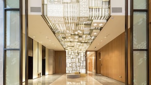 A spacious lobby with a reflective floor, a central seating area, and a decorative ceiling structure. - Hilton Garden Inn Zhuhai Hengqin (Zhuhai)