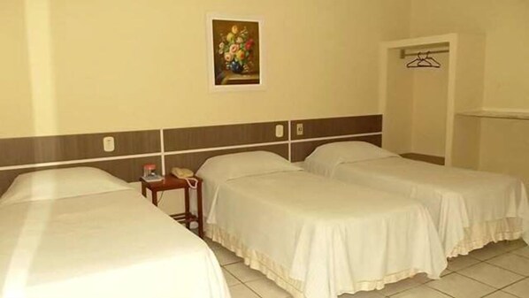 A hotel room with two beds, a small table with a telephone, and a painting on the wall.