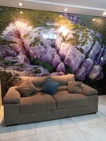 Un sofá color beige con dos almohadas frente a un mural grande que muestra rocas púrpuras y verdes.