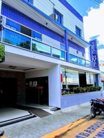 Un edificio con fachada azul y blanca, un letrero que dice "REAL HOTEL" y una motocicleta estacionada afuera.