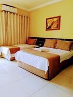 Habitación de hotel con dos camas, cortinas color crema, un cuadro en la pared y un equipo de aire acondicionado.