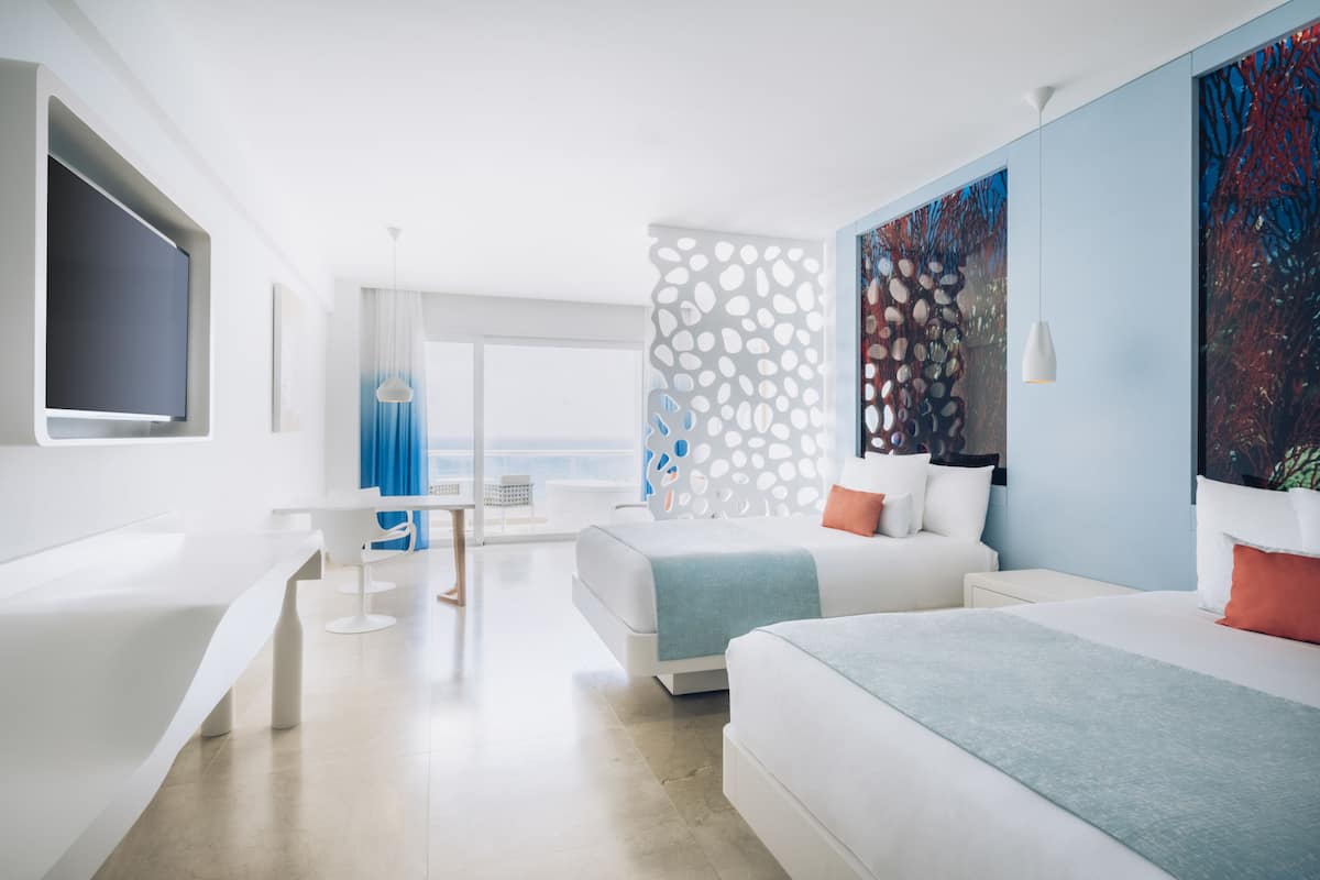 A modern hotel room with a large bed, a desk, and a TV.