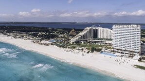 An aerial view of a beachfront hotel with multiple buildings, a pool area, and a beach. - Iberostar Selection Coral Cancún - Adults Only - All Inclusive (Cancun)
