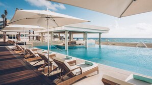 A poolside area with lounge chairs and umbrellas, a pool, and a view of the beach. - Iberostar Selection Coral Cancún - Adults Only - All Inclusive (Cancun)
