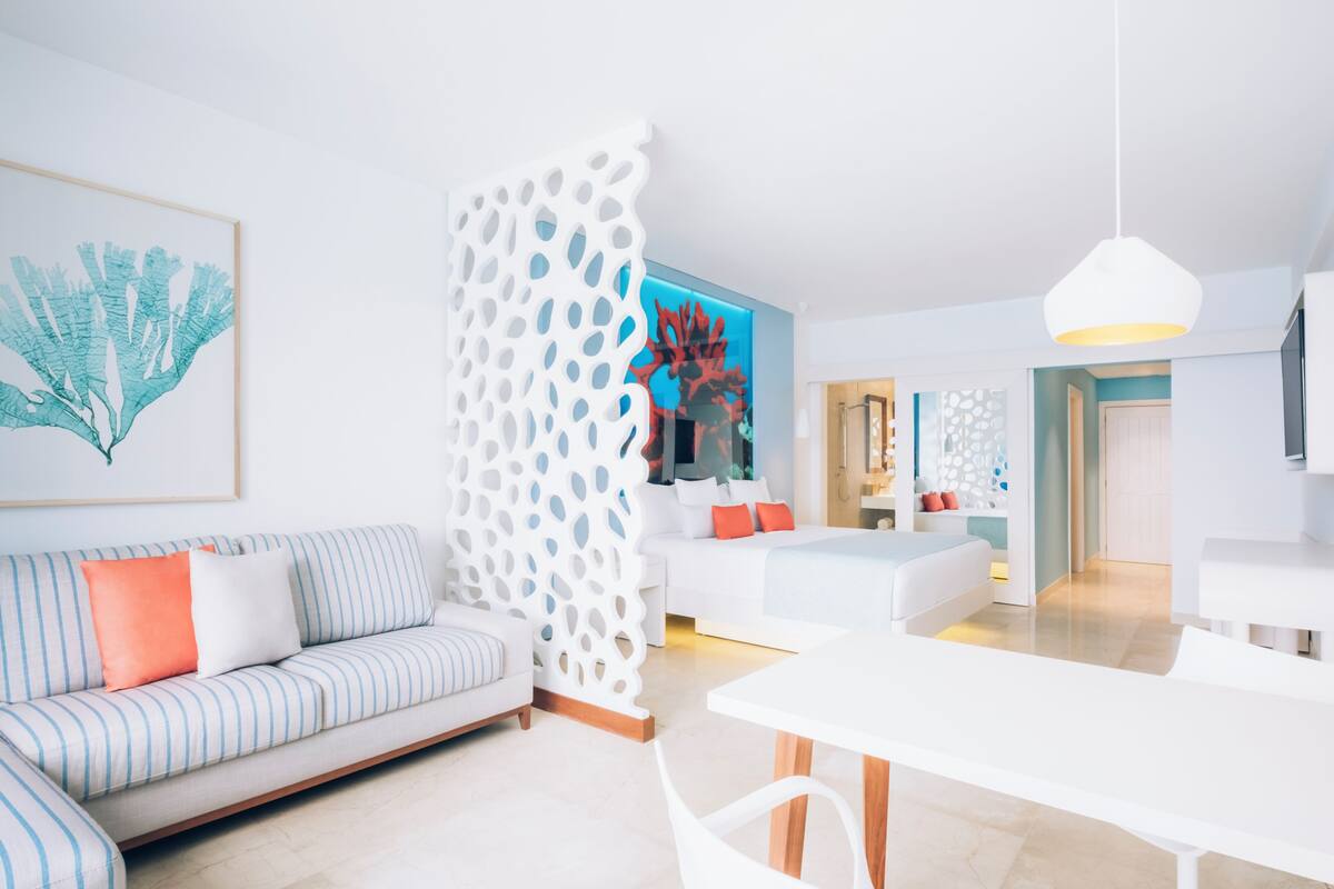 A modern living room with a sofa, a dining table, and a decorative white partition.