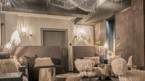 A modern interior with a sofa, chairs, and a wooden stool. - Hotel Blausee (Kandergrund)